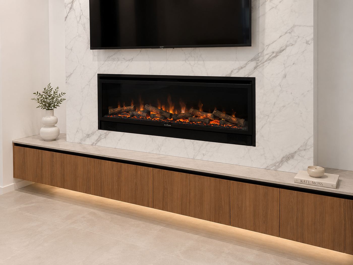 Living room joinery: a long floating walnut cabinet with a lit toe kick, marble surround, recessed linear fireplace and wall-mounted television.